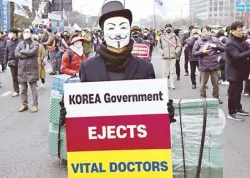  ?? AFP ?? A doctor wearing a mask holds a placard during a rally in Seoul on March 3.