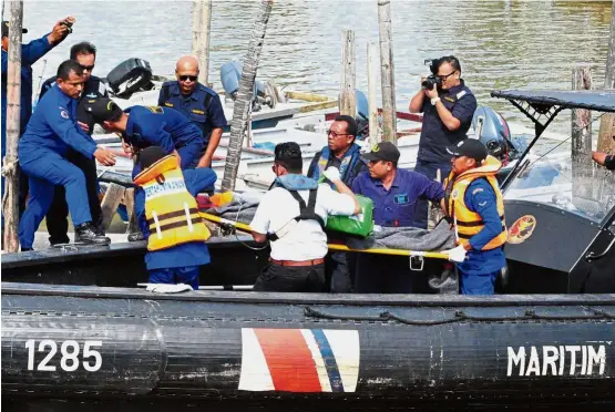  ??  ?? To safety: Rescuers carrying the 47-year-old Chinese national who was saved after being trapped in the sunken vessel’s engine room.