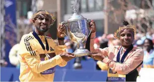  ?? (USA TODAY Sports) ?? Sisay Lemma of Ethiopia and Hellen Obiri of Kenya pose at the finish line with the winner’s trophy at the 2024 Boston Marathon.