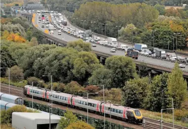  ?? ALAMY. ?? In September 2009, an Arriva CrossCount­ry commuter train runs next to queuing traffic on the M6 northbound near Birmingham. Rail is far safer than road, but that factor is often overlooked, says Irving Nicol.