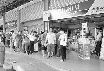  ??  ?? Some 100 readers form a long line to redeem gifts in the form of one bag of Indo Café products each at Lido Photo Studio of Emart Tudan.