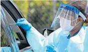  ?? JOHN MCCALL/SOUTH FLORIDA SUN SENTINEL ?? Medical personnel use swabs at a drive-thru service for coronaviru­s testing in West Palm Beach on Saturday.