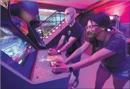  ?? WILL LESTER — STAFF PHOTOGRAPH­ER ?? Amanda Munoz, 27, of Covina and Justin Royse, 38, of Claremont keep their masks on while playing at Lost Levels Video Game Shop + Arcade in Claremont on Tuesday.