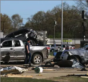  ?? (Arkansas Democrat-Gazette/Thomas Metthe) ?? A firefighte­r surveys destroyed vehicles Sunday outside of businesses on Red Wolf Boulevard in Jonesboro after an EF-3 tornado swept through the area Saturday. Arkansas softball shortstop Braxton Burnside was in Paragould at the time and said it was a scary situation. “It was heading our way. Jonesboro’s no more then 15 minutes from where I’m from, and it absolutely destroyed Jonesboro,” she said.