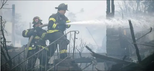  ?? KEITH BEDFORD/ REUTERS ?? Firefi ghters work to extinguish a fi re in New York on Tuesday. Superstorm Sandy has already caused an estimated $ 20 billion in property damage.