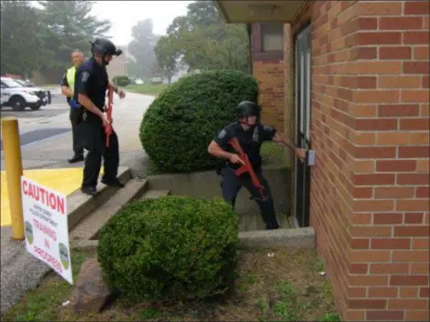  ?? KEVIN TUSTIN - DIGITAL FIRST MEDIA ?? Police officers to gain access inside through a side door at the school building. The front doors were locked as part of a live shooter scenario being practiced by police.