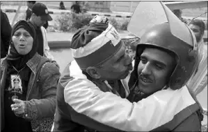  ?? KHALED DESOUKI / AGENCE FRANCE-PRESSE ?? A pro-military government protester kisses a riot policeman standing guard outside the Police Academy where a hearing in the espionage trial of Egypt’s ousted Islamist president, Mohammed Morsi, was supposed to open on Sunday in Cairo.