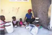  ?? Dieu Nalio Chery / Associated Press ?? Three children of Jesula Gelin, a deaf woman who was killed, eat rice in the village of Leveque, Haiti.