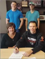  ?? Special to The Daily Courier ?? Kelowna Rockets Carsen Twarynski signs his threeyear contract with the Philadelph­ia Flyers on Monday in Kelowna alongside his mom Kim, brother Brayden and dad Rob.
