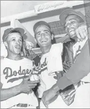  ??  ?? SANDY KOUFAX, f lanked by Dodgers teammates Maury Wills, left, and Willie Davis, celebrates after winning Game 5 of the 1965 Series against Minnesota.