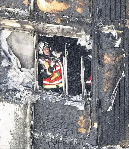  ?? Rick Findler ?? > A firefighte­r investigat­es a floor after a fire engulfed the 24-storey Grenfell Tower