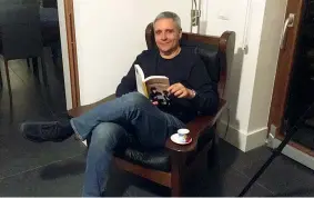  ??  ?? Lo scrittore Maurizio de Giovanni, nella sua casa a Napoli, con la poltrona da lettura dai braccioli a tavolino, perfetti per appoggiare la tazzina di caffè