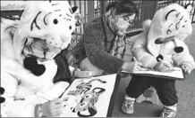  ?? XU CONGJUN / FOR CHINA DAILY ?? Children wearing tiger-head hats draw tigers during an activity welcoming the Year of the Tiger in the Chinese lunar calendar, which will start on Feb 1, in Nantong Forest Safari Park in Nantong, Jiangsu province, on Sunday.