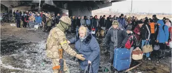  ?? ?? A Ukrainian serviceman helps evacuees gathered under a destroyed bridge, as they flee the city of Irpin, northwest of Kyiv (Photo by DIMITAR DILKOFF/AFP via Getty Images)