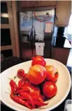  ??  ?? Left, pomegranat­es, chilies and cherry tomatoes add a splash of red to the kitchen. Right, wine and cookbooks line the wall.