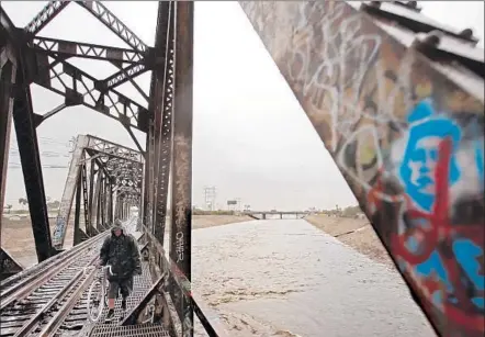  ?? GenaroMoli­na Los Angeles Times ?? THE L. A. RIVER, which at its peak canmove 146,000 cubic feet of water a second, passes under an old railroad bridge in South Gate.