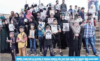  ?? —AFP ?? MOSUL: Iraqis hold up portraits of missing relatives who were held captive by Islamic State group fighters during a demonstrat­ion in the eastern part of this northern city on April 13, 2018.