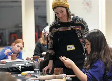  ?? ?? Artist Amy Hosterman helps New Vision Charter School student Valentina Bartels, 13, right, with her mug Wednesday.