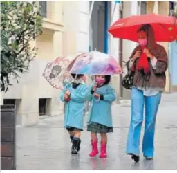  ??  ?? Niños camino del colegio equipados para la lluvia.