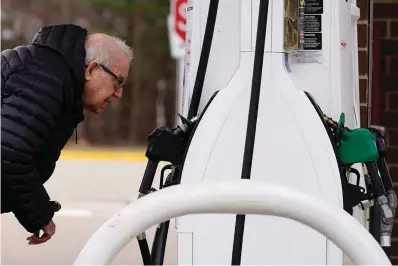  ?? The Associated Press ?? ■ A man checks gas prices on March 26 at a gas station in Buffalo Grove, Ill. President Joe Biden on Thursday ordered the release of 1 million barrels of oil per day from the nation’s strategic petroleum reserve for six months, a bid to control energy prices that have spiked after the United States and allies imposed steep sanctions on Russia over its invasion of Ukraine.