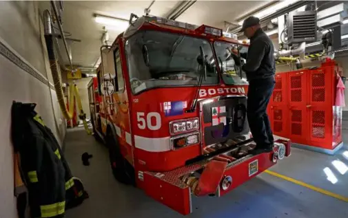  ?? DAVID L. RYAN/GLOBE STAFF ?? A firefighte­r cleaned a truck at Engine 50 firehouse in Charlestow­n.