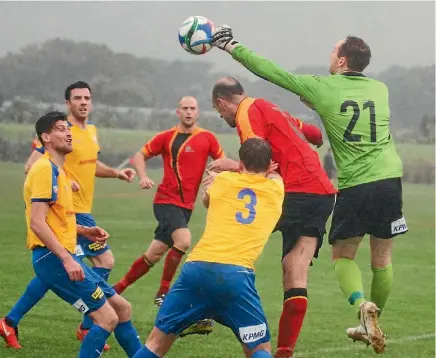  ??  ?? Western Suburbs goalkeeper punches the ball clear at a soggy Hutt Park in Wests 3-1 win over Stop Out