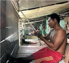  ??  ?? A man fixes a fishing net inside the longhouse.