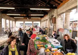  ??  ?? Shoppers browse among fresh food stalls under the cover of pillared walkways in the Buttermark­et. In Hay’s open-air castle bookshop, payment of £1 per book is made at the buyer’s discretion.