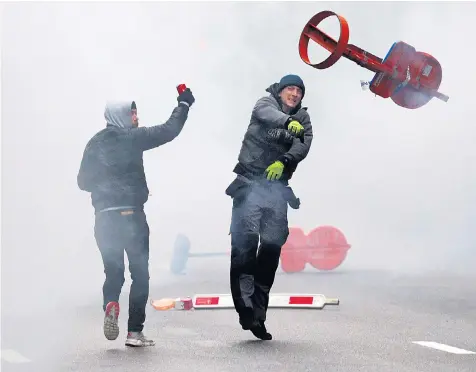  ??  ?? A far-right supporter throws a traffic sign during a protest in Brussels against the UN migration pact signed in Marrakesh last Monday