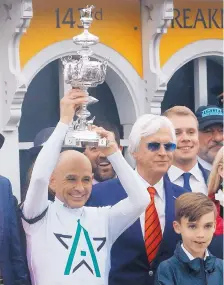  ??  ?? Jockey Mike Smith, a New Mexico native, holds the Woodlawn Vase after riding Justify to victory at the Preakness Stakes on May 19. Justify’s trainer, Bob Baffert, is at right.