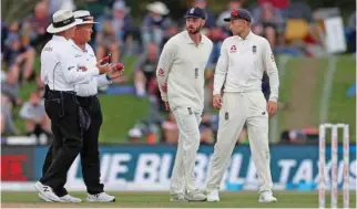  ?? – Reuters ?? EARLY END: England captain Joe Root, right, speaks with umpires after the play was suspended due to bad light on the fourth day of their second Test against New Zealand in Christchur­ch on Monday.