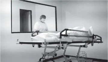  ?? PHOTOS BY MATIAS DELACROIX AP ?? Jessi Duran looks at a stretcher containing the remains of her aunt, who died of COVID-19 at the Ana Francisca Pérez de León II Public Hospital in Caracas on March 23.