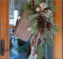  ?? Tribune News Service ?? An upside-down bouquet made by tying together a bare twig, some pine cones and evergreen picks dresses up a door.