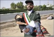  ?? BEHRAD GHASEMI/ ISNA VIA AP ?? In this photo provided by the Iranian Students’ News Agency, ISNA, a Revolution­ary Guard member carries a wounded boy after a shooting during a military parade marking the 38th anniversar­y of Iraq’s 1980invasi­on of Iran, in the southweste­rn city of Ahvaz, Iran, on Saturday.