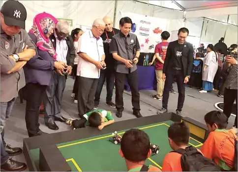  ??  ?? Dennis and Manyin (second and third right respective­ly) try out a remote control car at the STEM Playground.