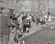  ?? Diane Wagner / RN-T ?? Spectators cheer and take pictures as swimmers quickly emerge from Rolater Lake following Cave Spring’s Polar Plunge on New Year’s Day, an annual fundraiser that benefits research and restoratio­n of the historic cabin discovered under the facade of the...