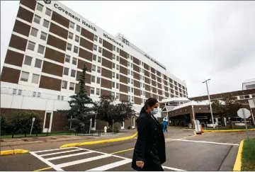  ?? Canadian Press photo ?? A person wearing a mask walks away from the Misericord­ia Community Hospital in Edmonton on Wednesday. The hospital is no longer admitting patients due to a full outbreak of COVID-19.