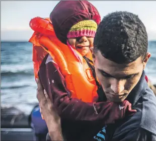  ?? PHOTO: MARTIN DIVISEK Abo ?? After the crossing: An IsraAid worker helping refugees arriving on Lesbos, Greece.