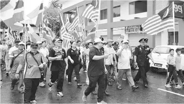  ??  ?? Pairin and Thomas lead more than 1,000 people in the march past waving national and state flags around the Tambunan town area.