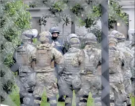  ?? TED S. WARREN / AP ?? A Washington State Patrol trooper talks with members of the Washington National Guard inside a fence surroundin­g the Capitol in anticipati­on of protests Monday in Olympia, Wash.