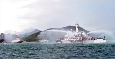  ?? SHA XIAOFENG / FOR CHINA DAILY ?? A Chinese Coast Guard vessel performs a fire suppressio­n drill with a fishing boat in Sanya, Hainan province, on Thursday. The drill, which simulated a collision between a fishing boat and a passenger vessel, was organized by the city’s maritime search...