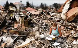  ?? GARY CORONADO / LOS ANGELES TIMES ?? Maureen Kissick, sitting in the remains of her dining room, looks through what is left of her Noritake Tahoe China, from her wedding 36 years ago, in the wake of the Carr Fire in Redding, Calif., on Saturday.