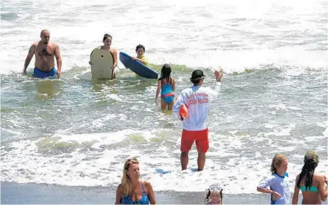  ?? JOE CAVARETTA/STAFF PHOTOGRAPH­ER ?? A Boca Raton lifeguard warns swimmers Sunday, at South Ocean Park. High winds and riptides caused caution flags to be raised on beaches .