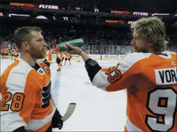  ?? TOM MIHALEK ?? Flyers captain Claude Giroux, left, gettinng a drink of water from Jakub Voracek before Tuesday’s 8-2 drubbing by the Sharks in the home opener, said it’ too early for Flyers fans to push the panic button.