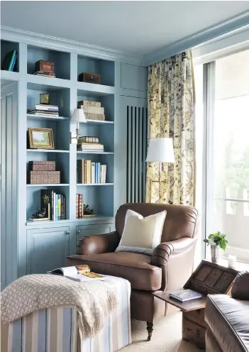  ?? ANGIE SECKINGER/SHERRY MOELLER ?? An ottoman helps turn a comfortabl­e living room chair into the perfect place for reading, exemplifie­d by this home library designed by Kelley Proxmire.