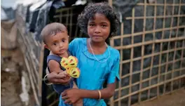  ?? — AP ?? A Rohingya Muslim girl carries a child at a makeshift camp near Kutupalong refugee camp in Cox’s Bazar, Bangladesh, on Tuesday.