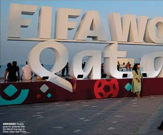  ?? ?? AWKWARD: People pose for pictures with the World Cup sign in Doha, Qatar last Friday