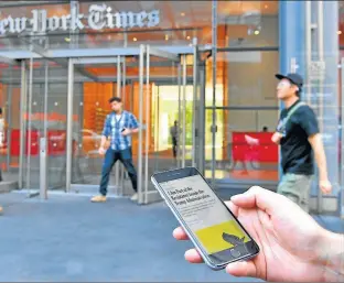  ?? AFP ?? persona lee virtualmen­te el archivo frente al edificio delen Nueva York.