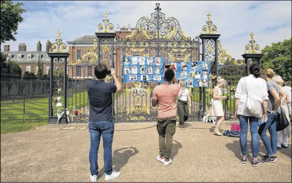  ?? IsAbeL infAnTes/The AssociATed Press ?? People look at messages and flowers attached to the Golden Gates of Kensington Palace in London, ahead of the 20th anniversar­y of Princess Diana’s death. The way Princess Diana died in a high-speed Paris car crash — while she and her boyfriend were...