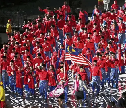  ?? — GLENN GUAN / The Star ?? Here we go: Malaysia’s flag-bearer Hakimi Ismail leading the contingent during the march-past at the 2018 Commonweal­th Games opening ceremony at the Carrara Stadium in Gold Coast, Australia, yesterday. Left: Fireworks lighting up the sky.